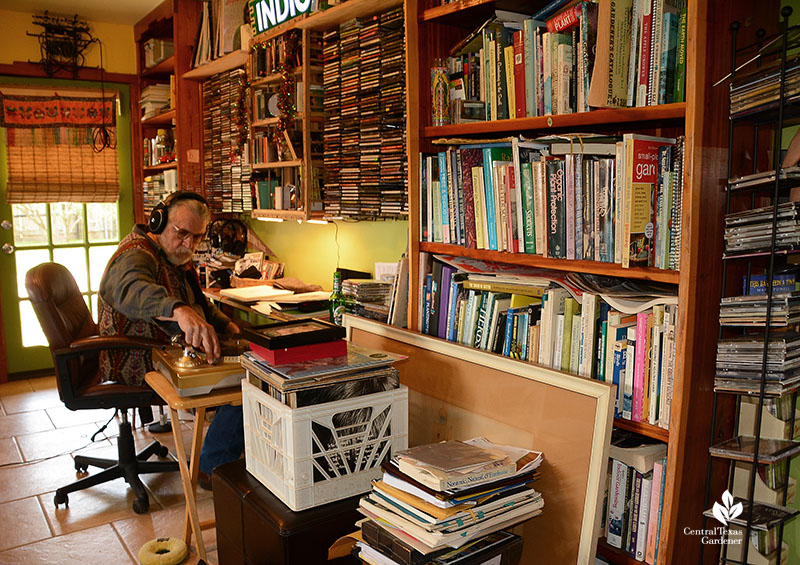 man at desk checking out music; many bookcases filled with record albums