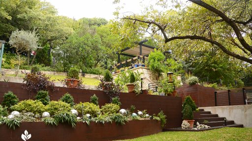 steel planters and retaining wall to upper outdoor living area sloped yard design Duhon Harper