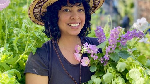 smiling woman in garden hat holding bouquet of flowers