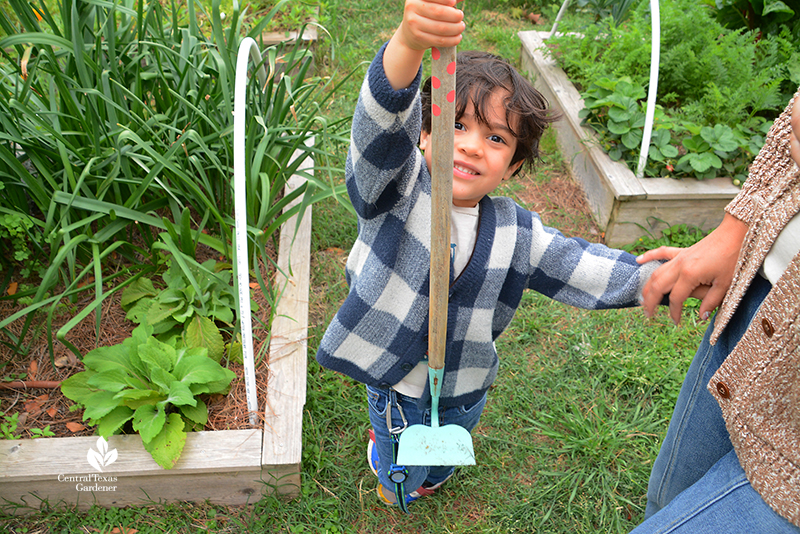 child with hoe La Otra Flora garden 