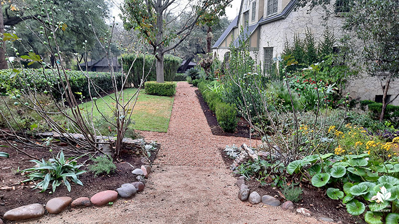 gravel path bordered by gardens and small trees