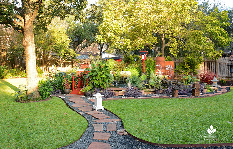 gravel and stone path through lawn to red bridge and garden island