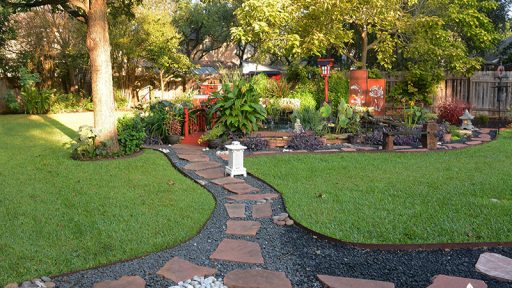 gravel and rock path through lawn to colorful garden island