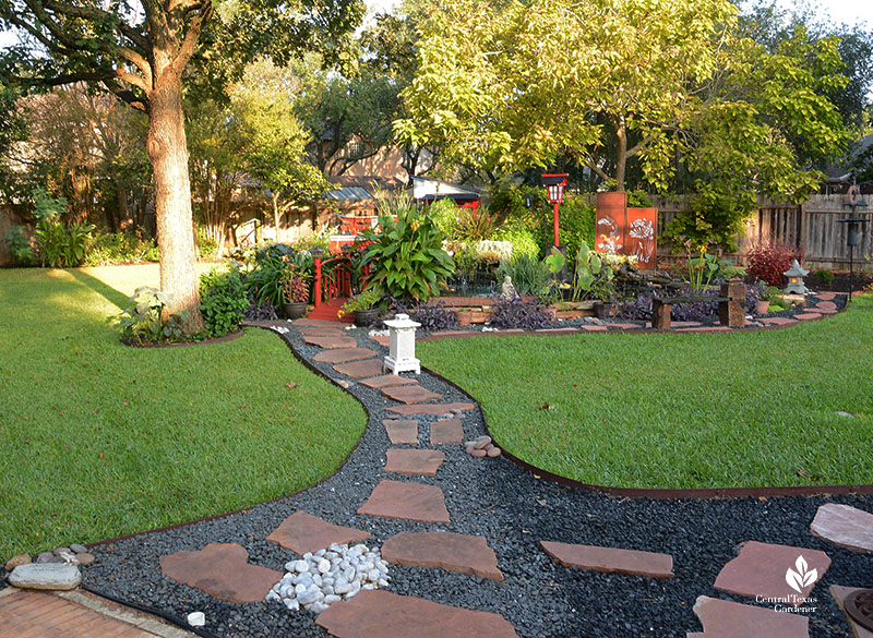 gravel and rock path through lawn to colorful garden island