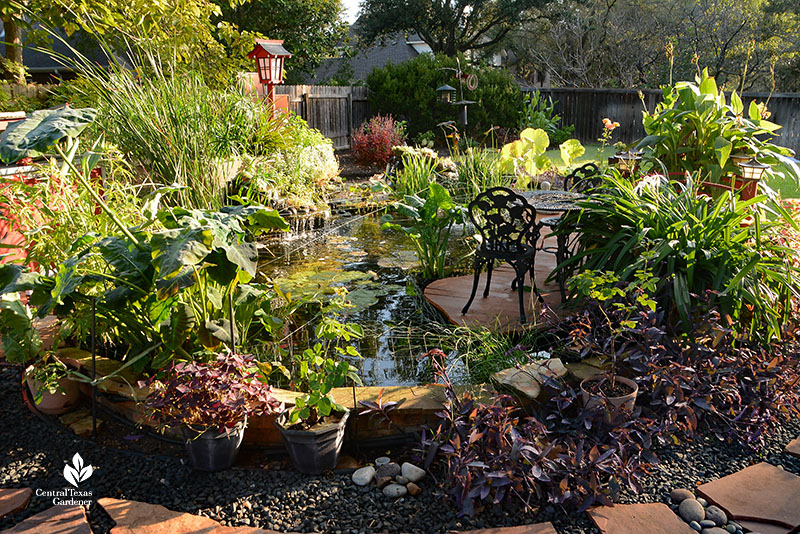 stone path pond waterfalls plants with bistro table on deck