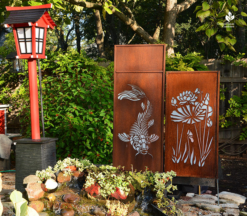 metal panels cut out in shape of fish and plant next to red Japanese lantern
