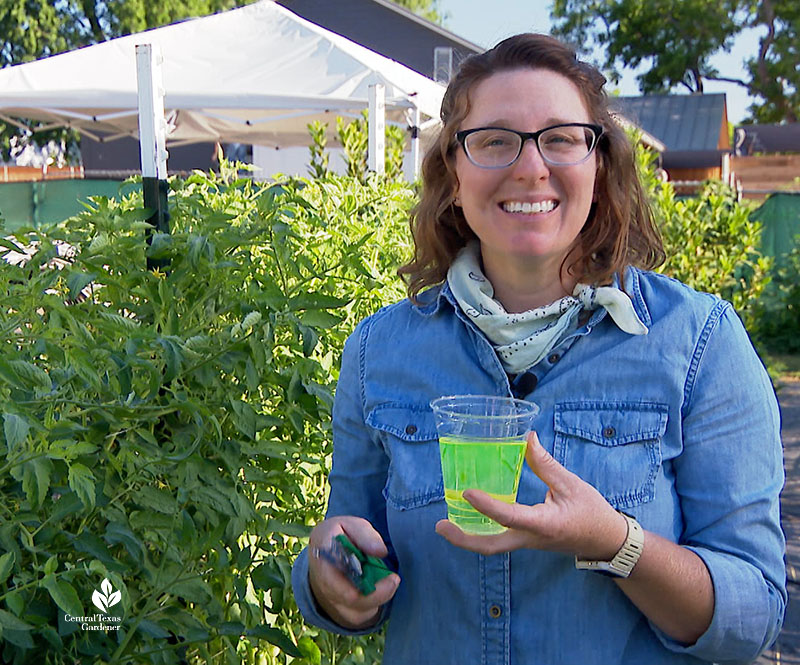 woman holding cup of green liquid with pruners in other hand