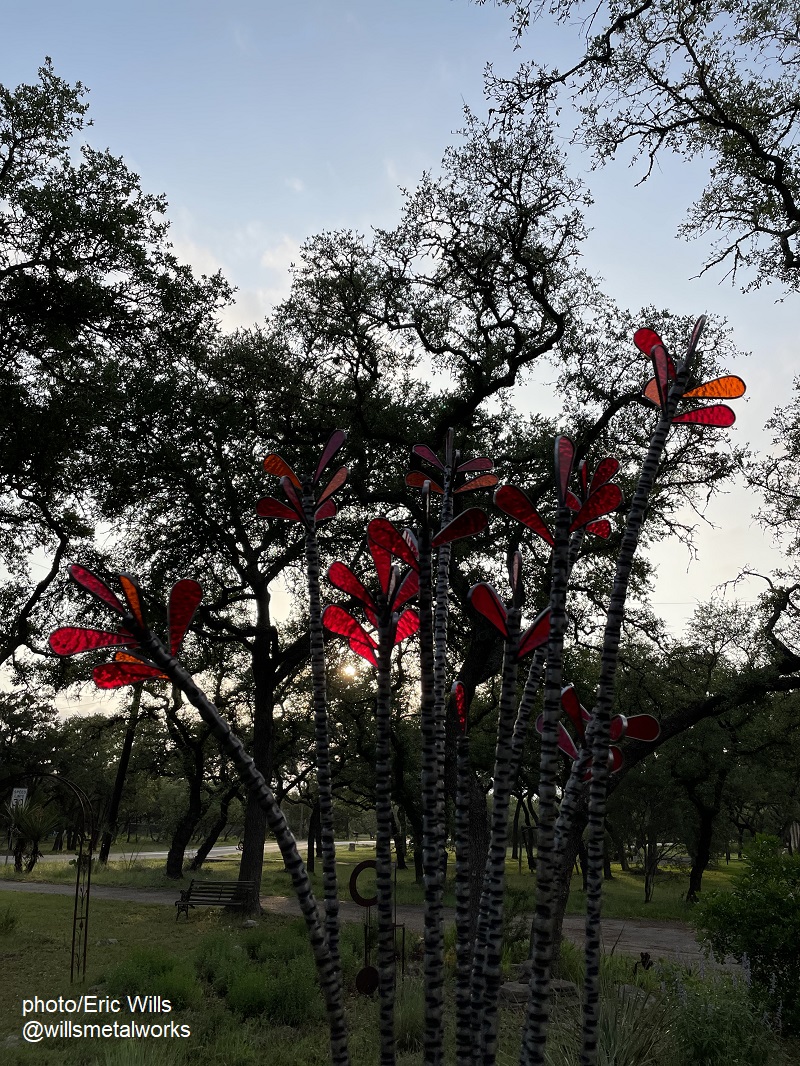 red glass flowers in metal sculpture glow in sunset 