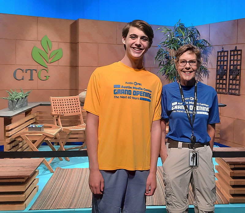 young man in gold volunteer shirt; woman in blue Grand Opening shirt on CTG studio set