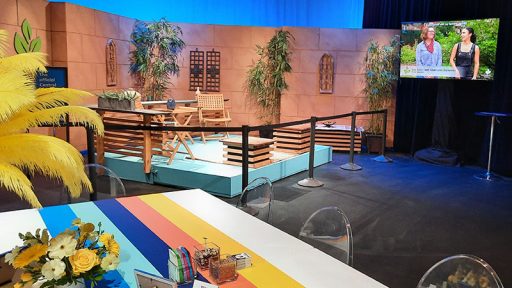 table with flowers in studio with CTG set beyond and TV monitor on wall