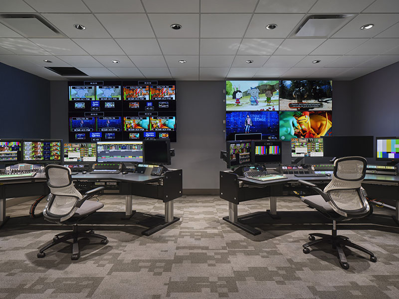 desks and chairs in front of several monitors for master control operations broadcast programs 
