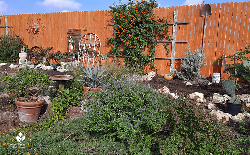 backyard mound (berm) with plants, trellis, garden art