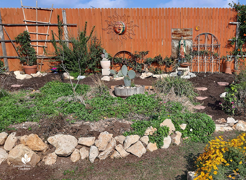 backyard mound (berm) bordered by limestone rocks and small plants in middle