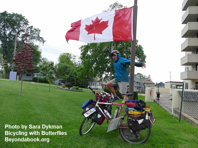 woman on bike in front of Canadian red and white flag