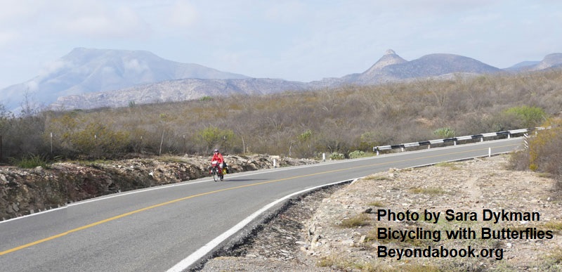 bicyclist on highway stretch with mountains in background