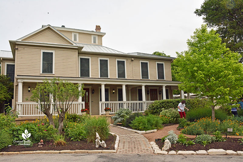 large old farmhouse with gardens in front 