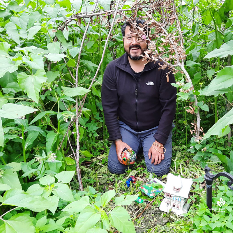 smiling man in woven tree and plant limb "tent" 