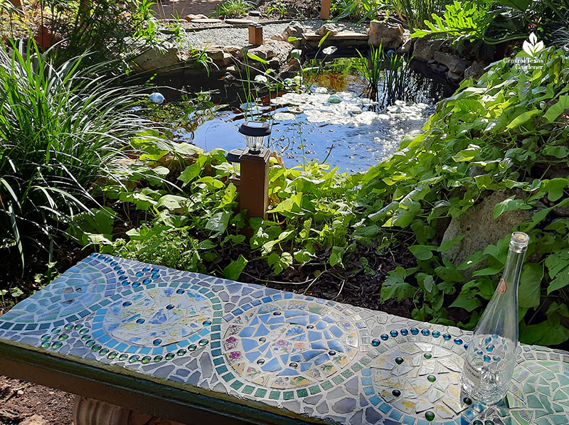 mosaic bench in front of pond