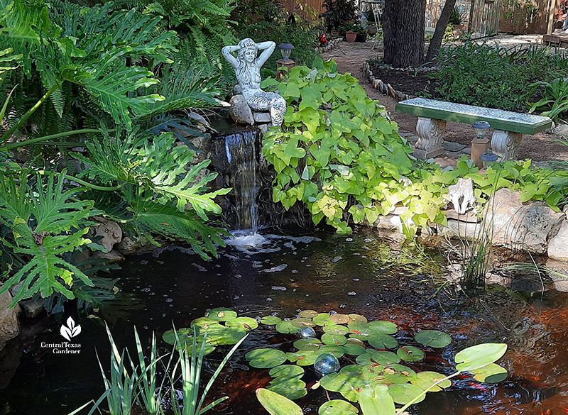 mermaid sculpture atop small waterfall 