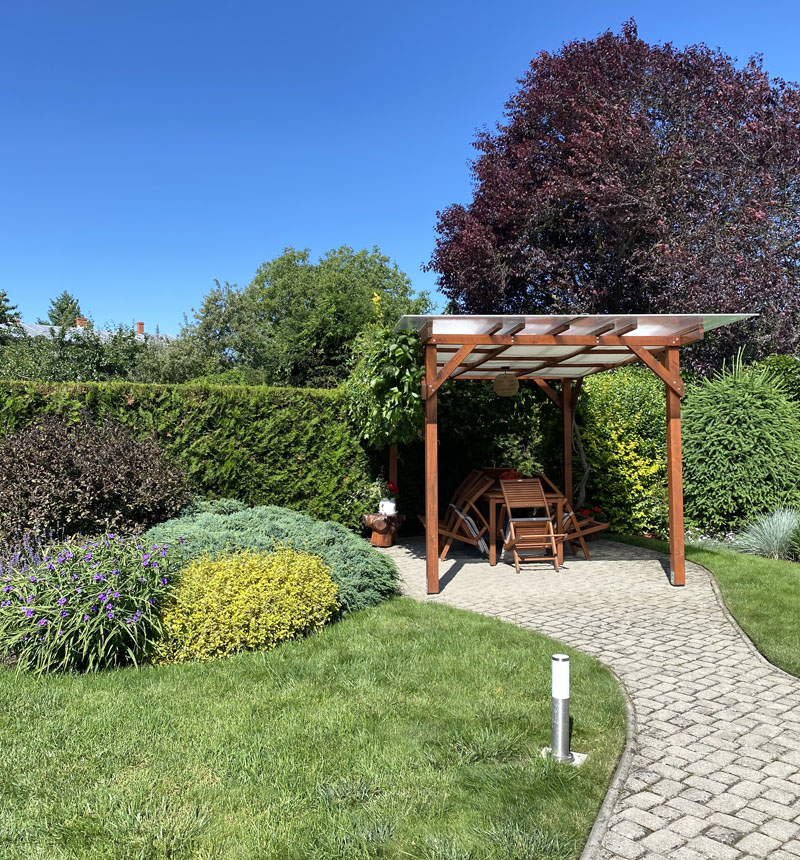 path to chair in arbor against garden hedge