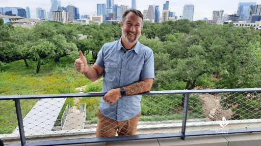 man on roof overlooking green space against high rise buildings