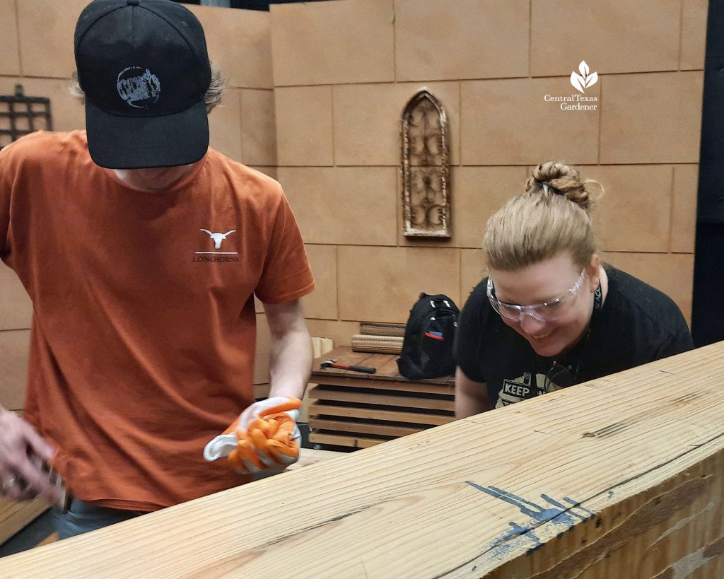 college student and young woman with safety goggles drilling TV studio set furniture