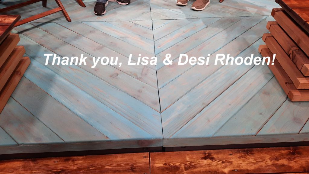 light blue platform with words Thank you, Lisa and Desi Rhoden. 