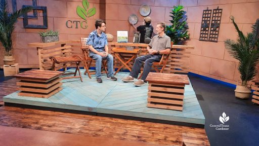 two men on studio set plaform while another arranges baskets on the wall