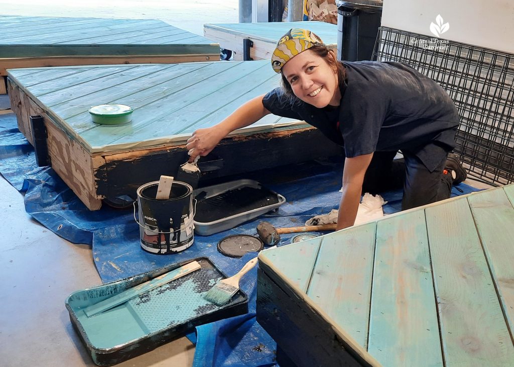 young woman painting sides of platform