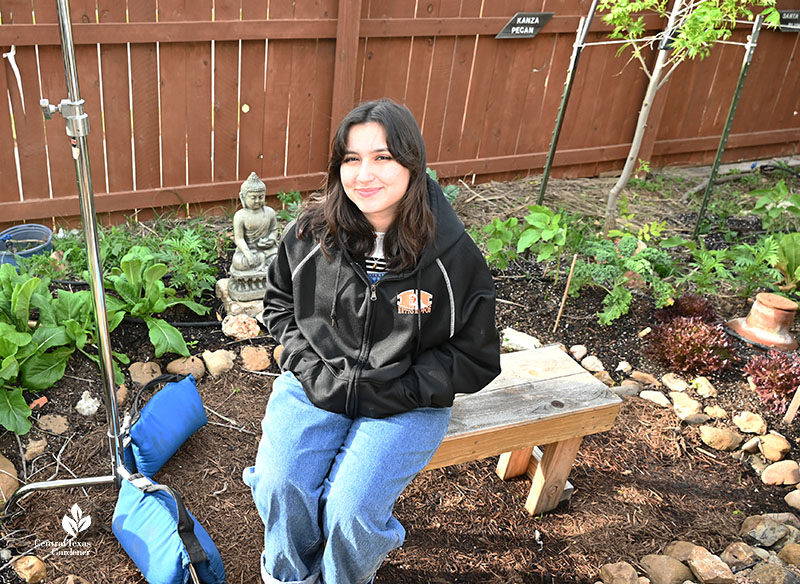 young woman on garden bench in a backyard