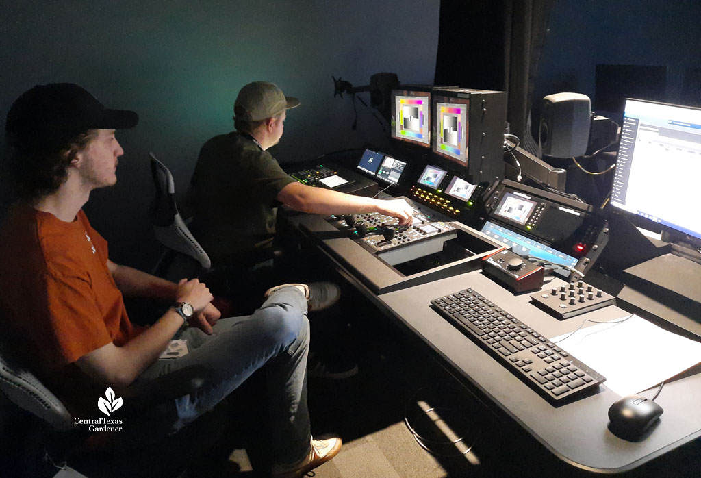 two men in control room looking at monitors 