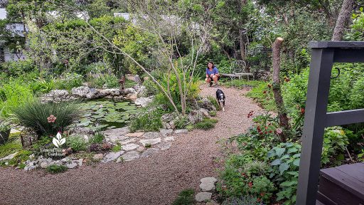 woman and dog on gravel path around backyard pond