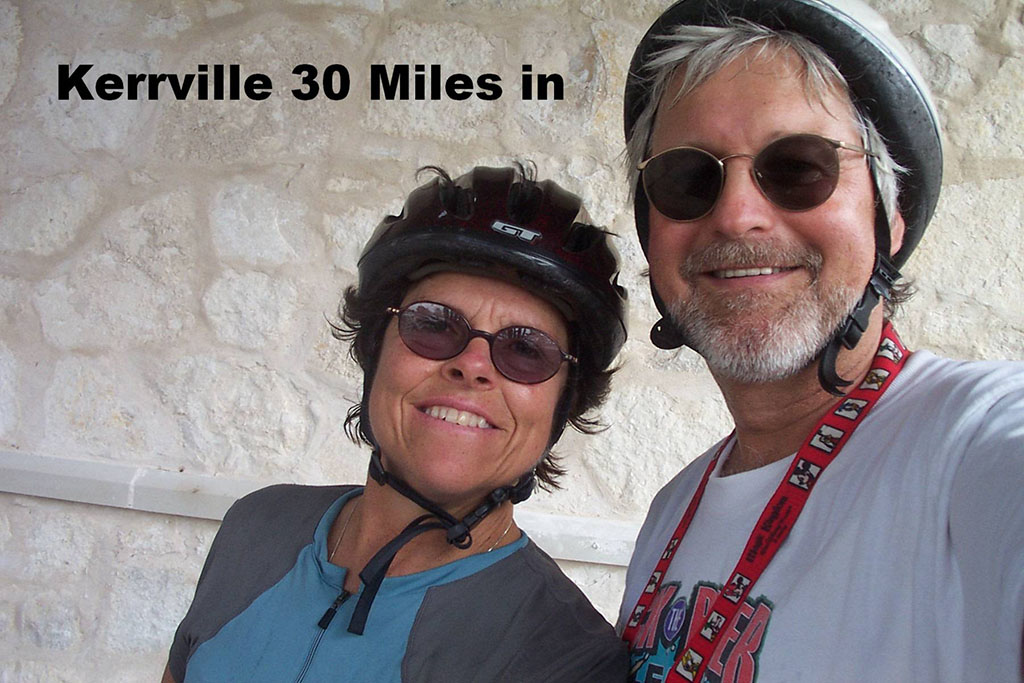 smiling woman and man wearing bike helmets text says "Kerrville 30 Miles In" 