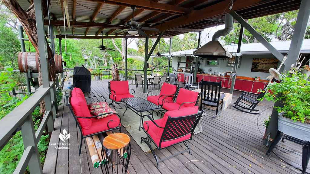 large casual wooden deck patio with red furniture and kitchen along one wall