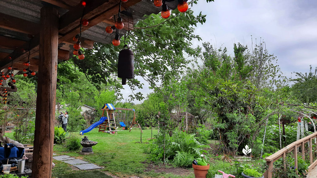 lawn, twig hut, gardens and swing set in backyard 