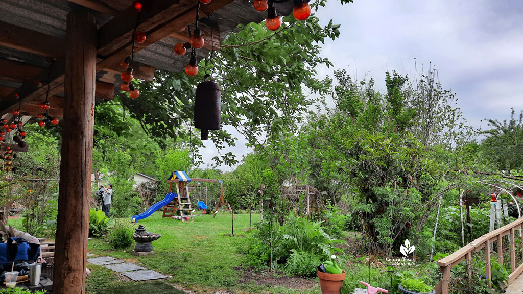 lawn, twig hut, gardens and swing set in backyard 