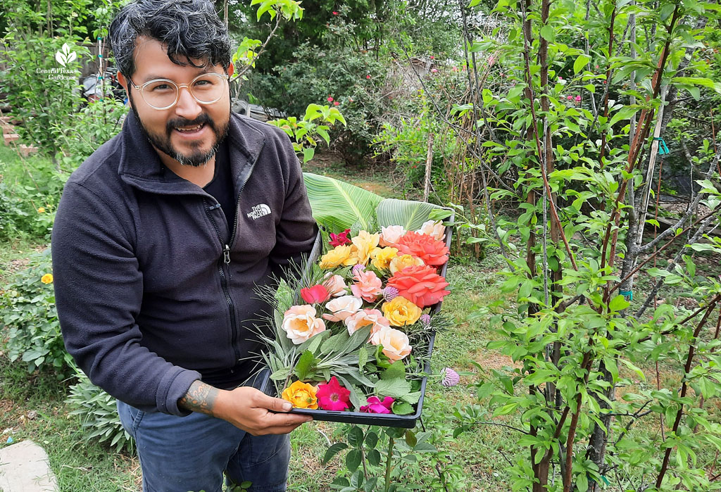 smiling man holding a try of rose flowers of all different colors