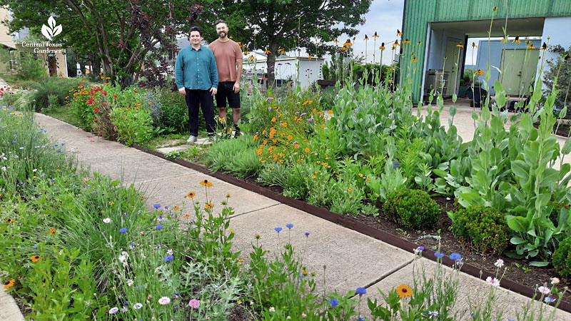 two men smiling and waving in front yard garden 