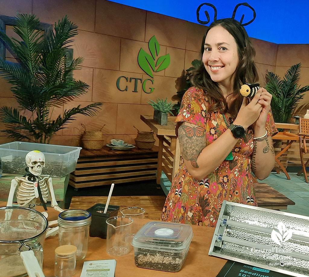 smiling woman on CTG set holding stuffed animal monarch caterpillar 