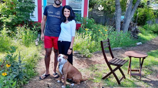 man and woman with dog in front of red and white shed