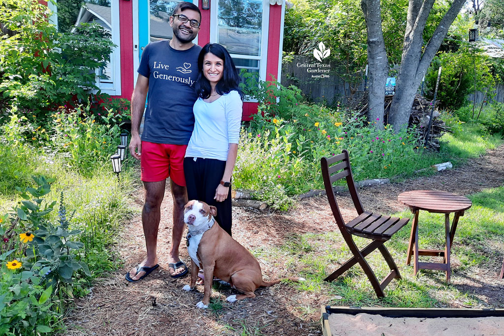 man and woman with dog in front of red and white shed