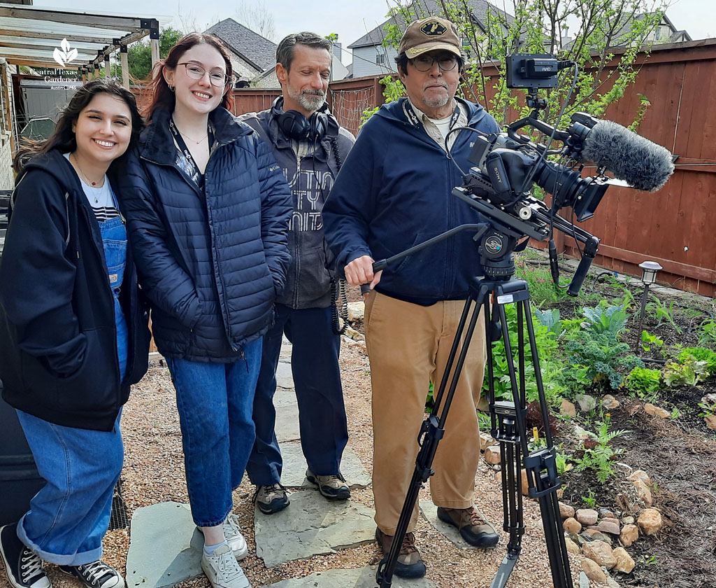 two women and two men with video camera in a garden