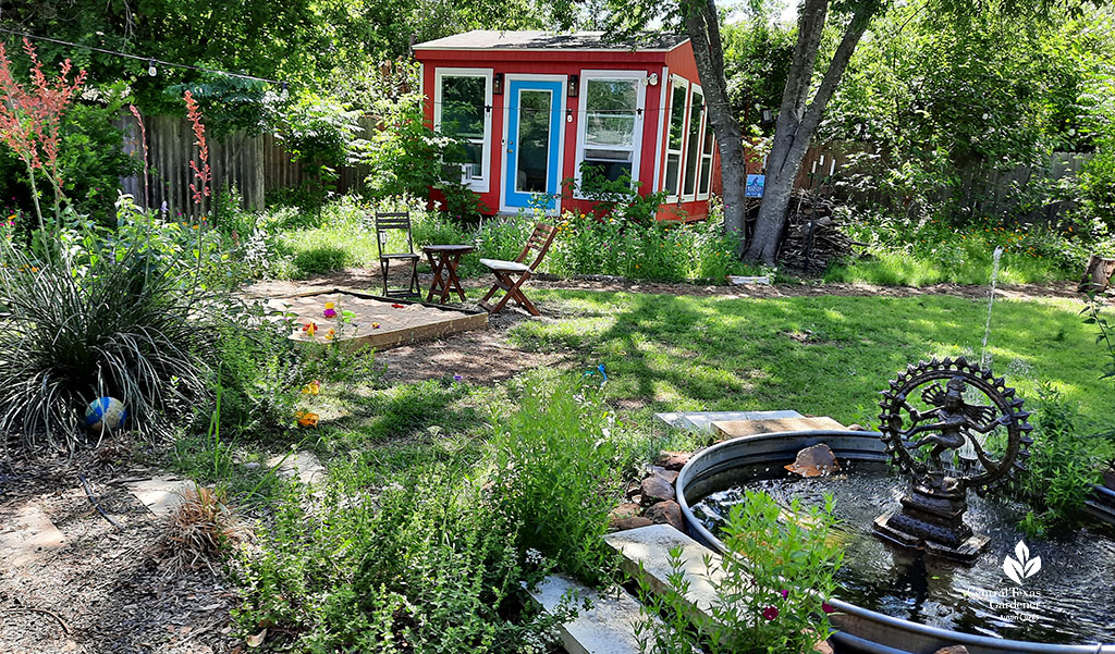 stock tank pond to backyard view with sandbox and red, white and blue shed