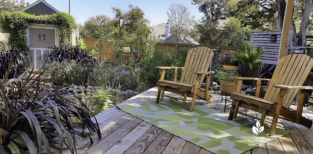 adirondack chairs on wood deck overlooking colorful flowers and grasses 