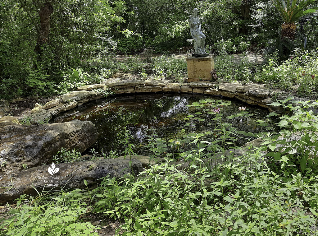 native stone edged pond framed by plants and tall sculpture