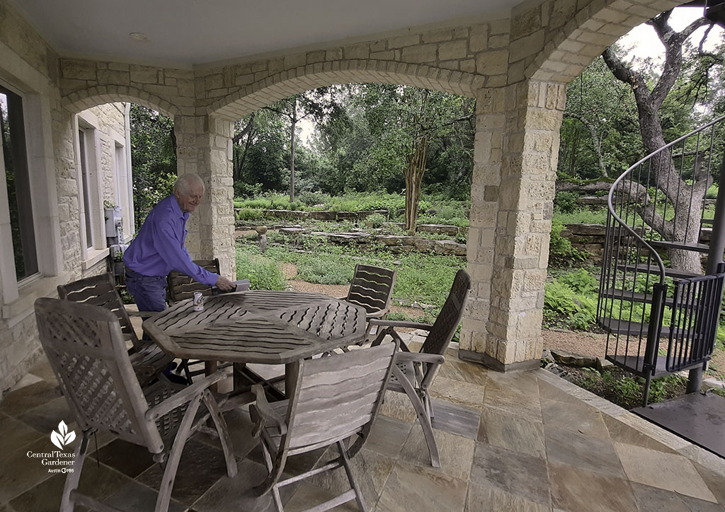 smiling man on limestone framed patio overlooking stone walls and native plants 