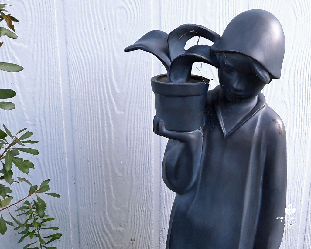dark gray metallic-looking sculpture young girl holding a plant
