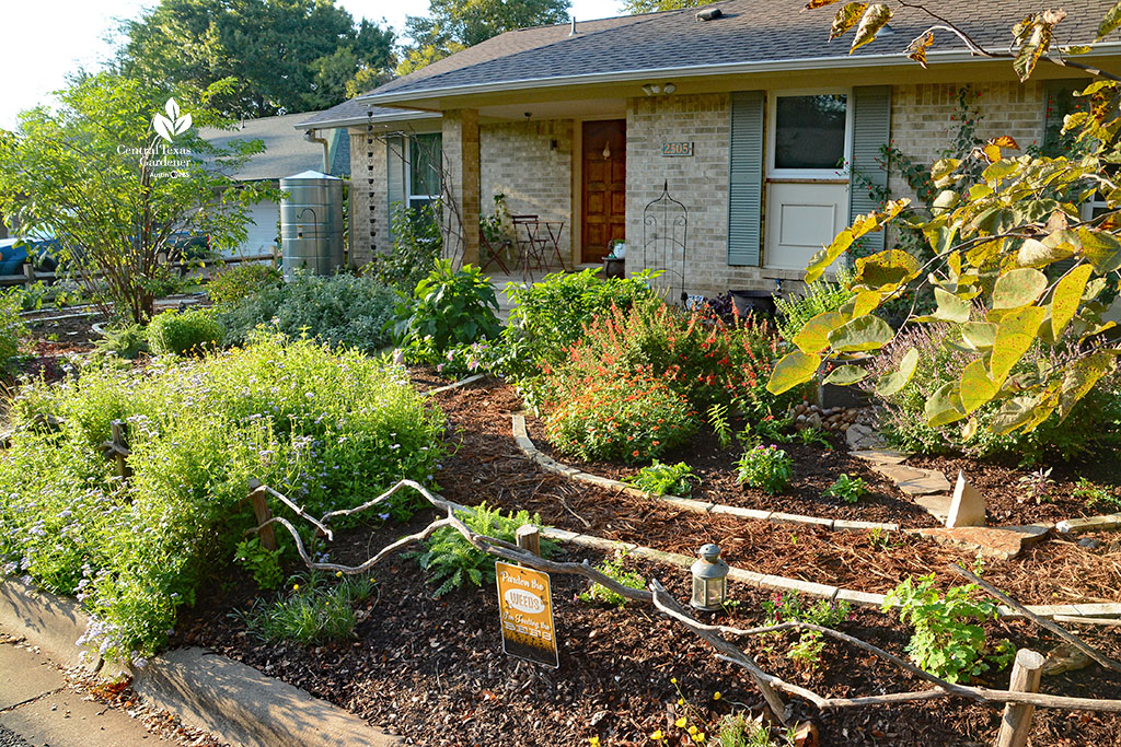 front yard garden with rock-lined mulch path through flower-filled beds 