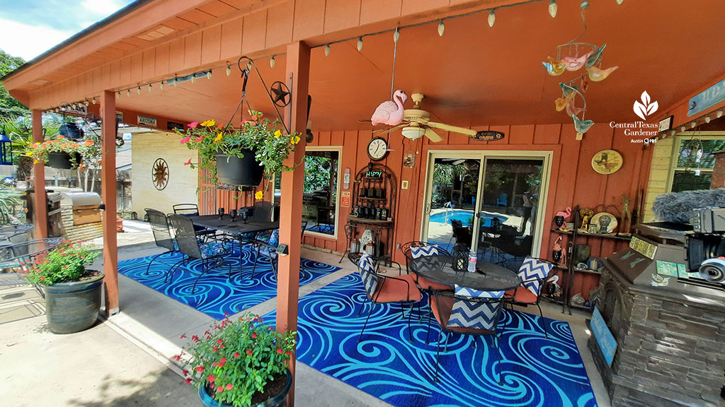 long covered patio, walls painted a warm umber, with blue patterned rug, artwork, and dining tables 