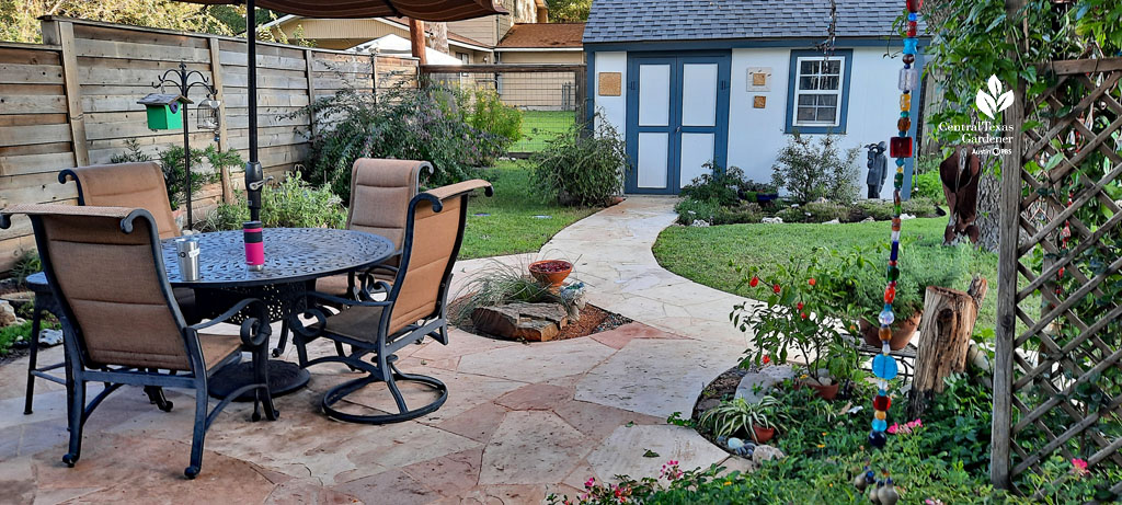 pale orange/white stone patio umbrella table, walkway to blue and white shed